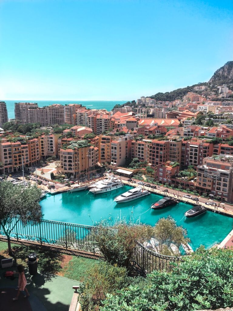 A stunning aerial view of Monte Carlo's vibrant harbor and surrounding cityscape under a clear blue sky.