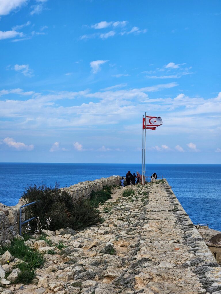 Historic Kyrenia Castle with flags overlooking the sea on a bright day.