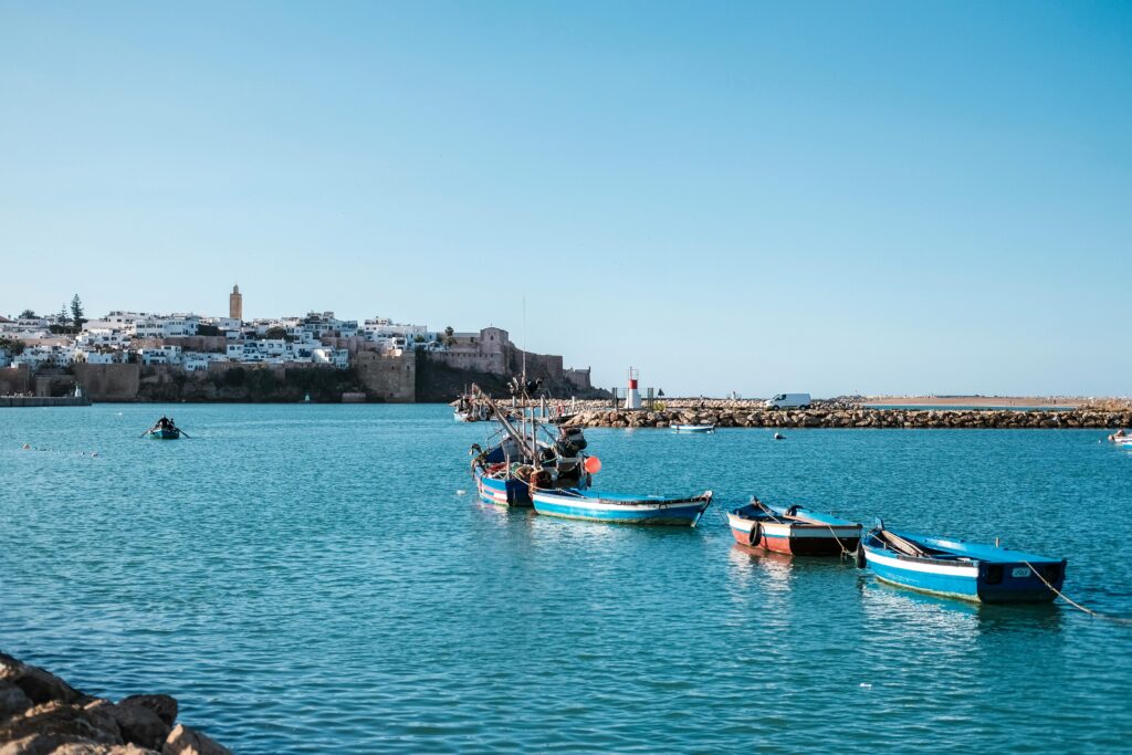 Calm waters and colorful boats with Rabat's historic architecture in the background.